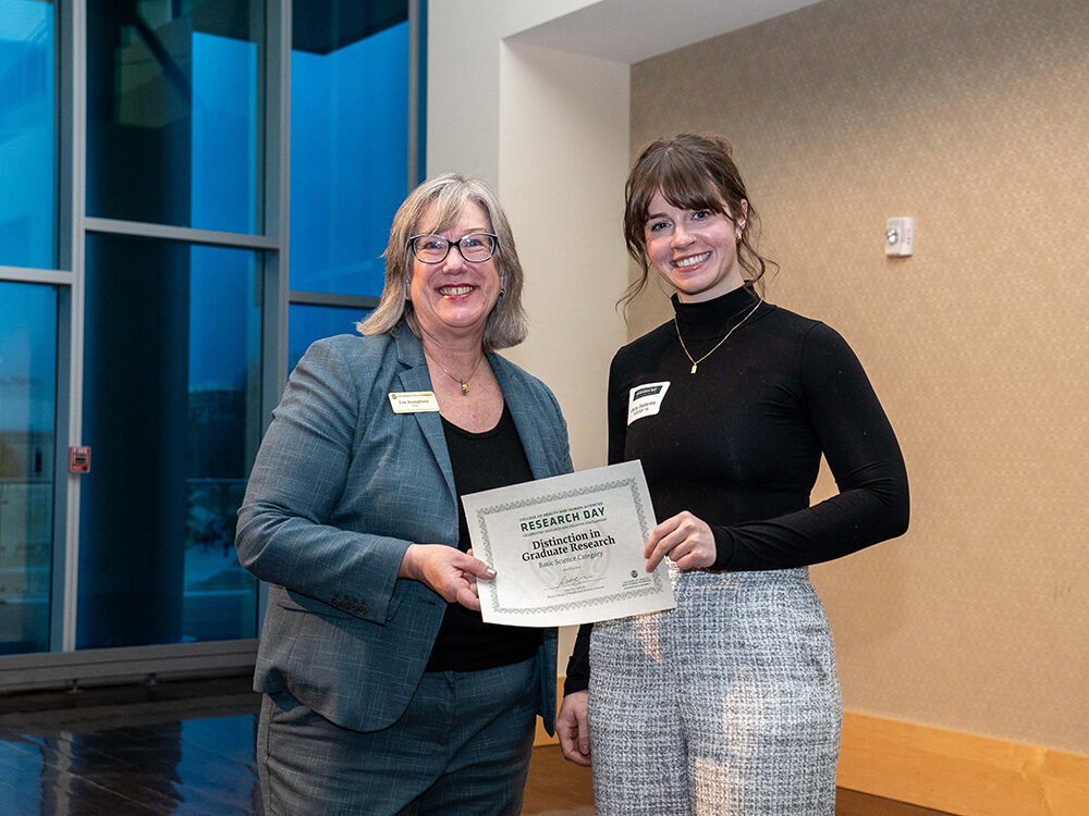 Lise Youngblade presenting Darby Easterday with the Basic Science - Distinction in Graduate Research award at Research Day 2024