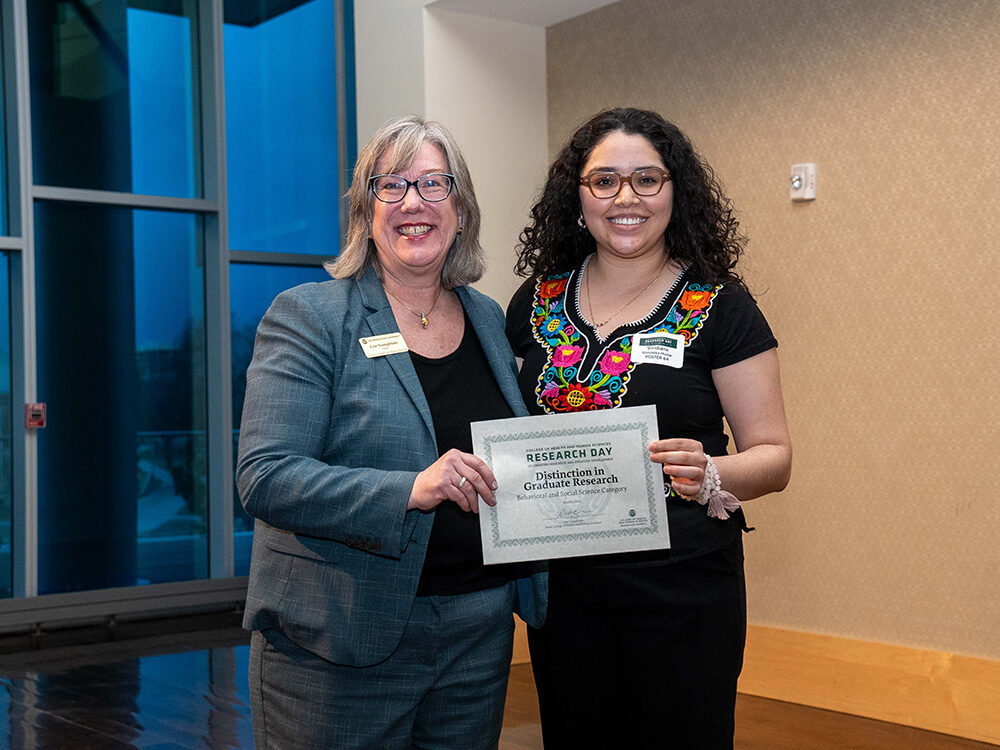 Lise Youngblade presenting Viridiana Gonzalez Huizar with the Behavioral and Social Science - Distinction in Graduate Research award at Research Day 2024