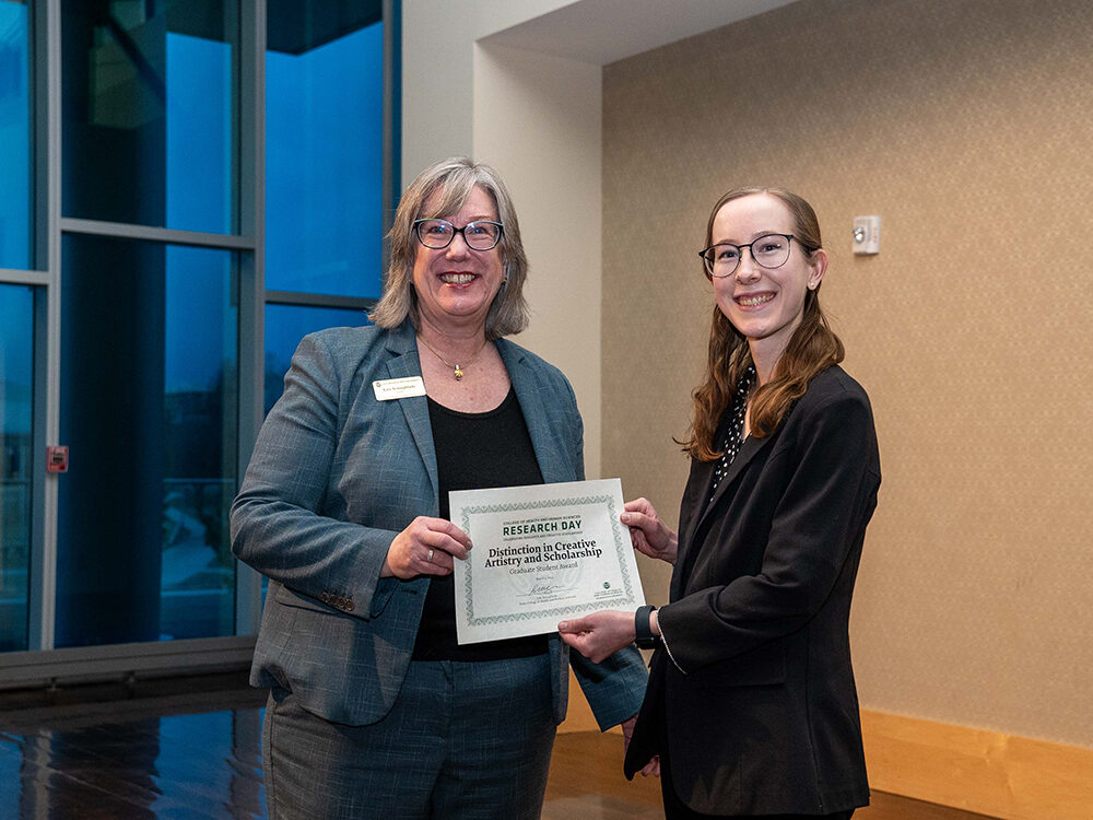 Lise Youngblade presenting Rachel Anderson with the Distinction in Creative Artistry and Scholarship Graduate Student award at Research Day 2024