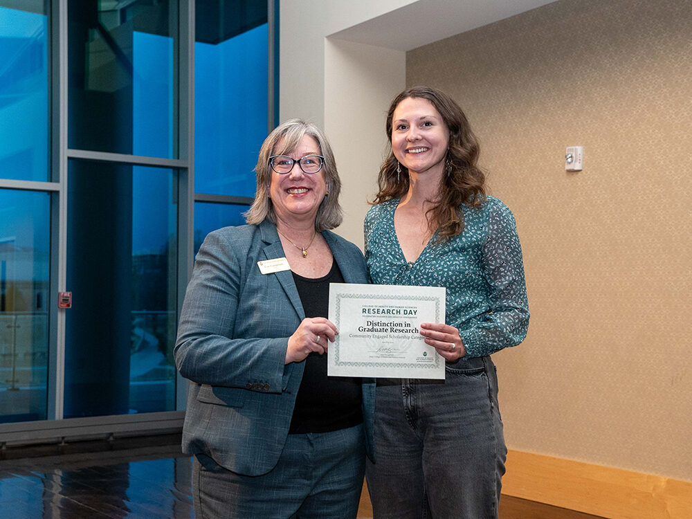Lise Youngblade presenting India Luxton with the Community Engaged Scholarship award at Research Day 2024