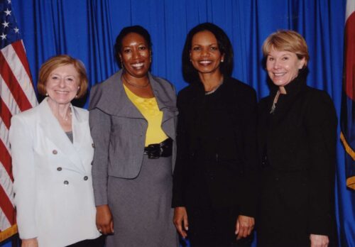 Nancy Hartley, Eulanda Sanders, and Jodie Hanzlik with Condoleezza Rice in front of a blue curtain and a flag