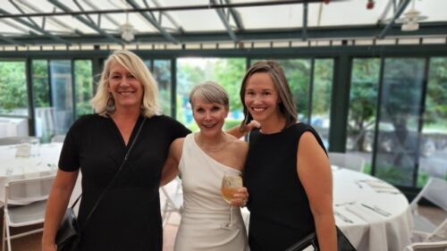 Jodie wearing a fancy white dress surrounded by two women wearing black dresses