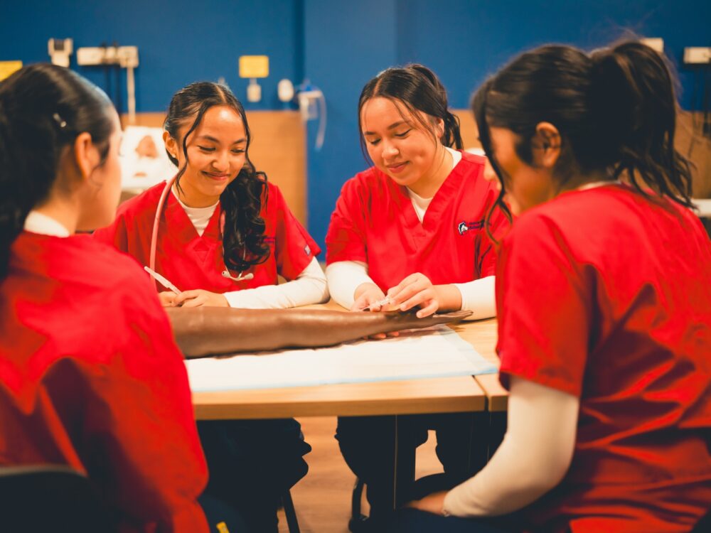 A group of nursing students smile while working in a hospital setting.