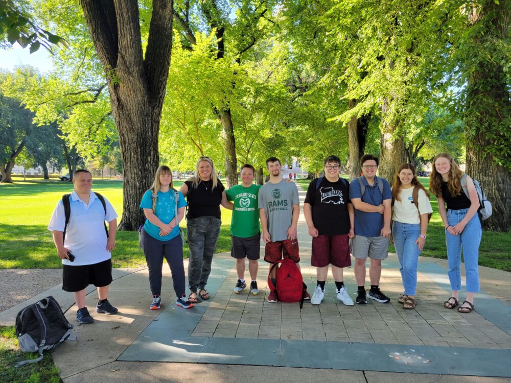 RAM Scholars pose on campus with green trees surrounding them.