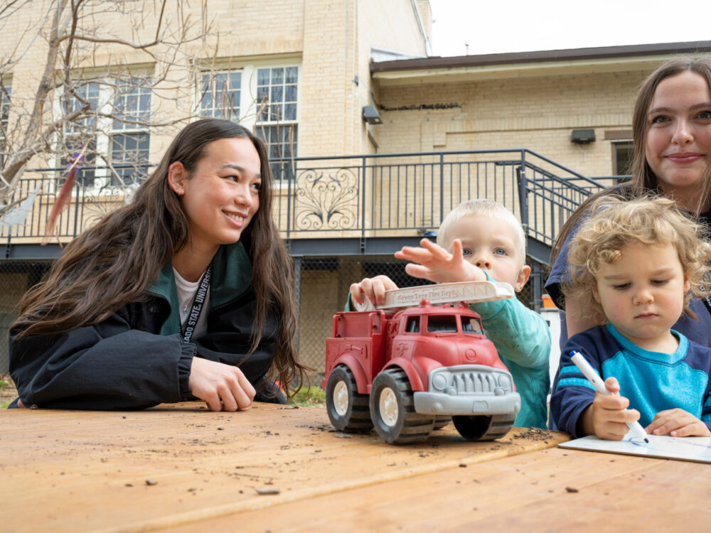 Two CSU students play with children and trucks outside