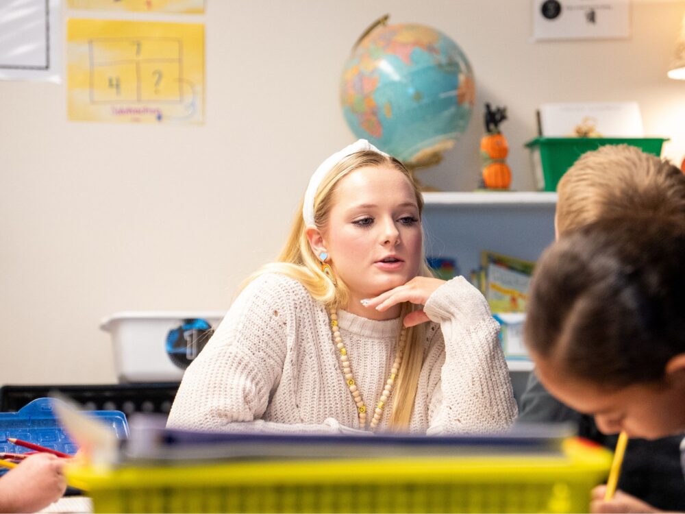 A CSU student smiles in a classroom while teaching young children.