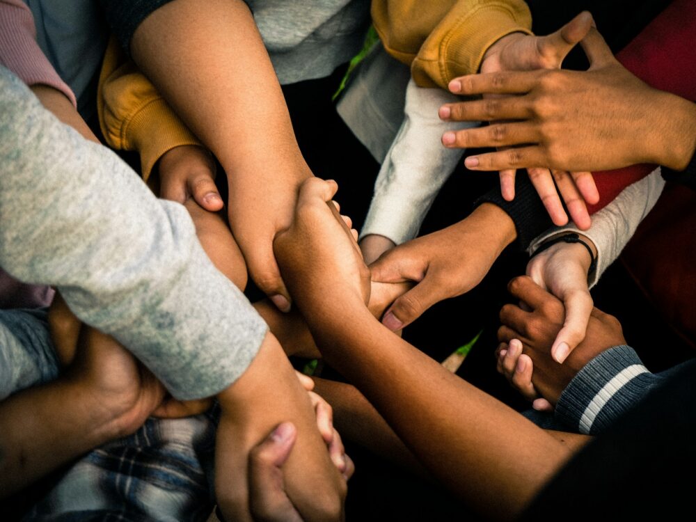 A close-up photo of young people's hands from various ethnic backgrounds.